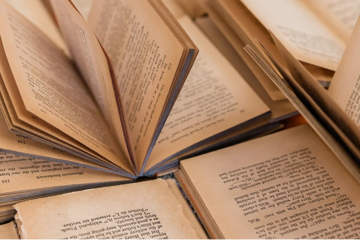 Stack of freshly printed paperback books on a desk beside an open manuscript document